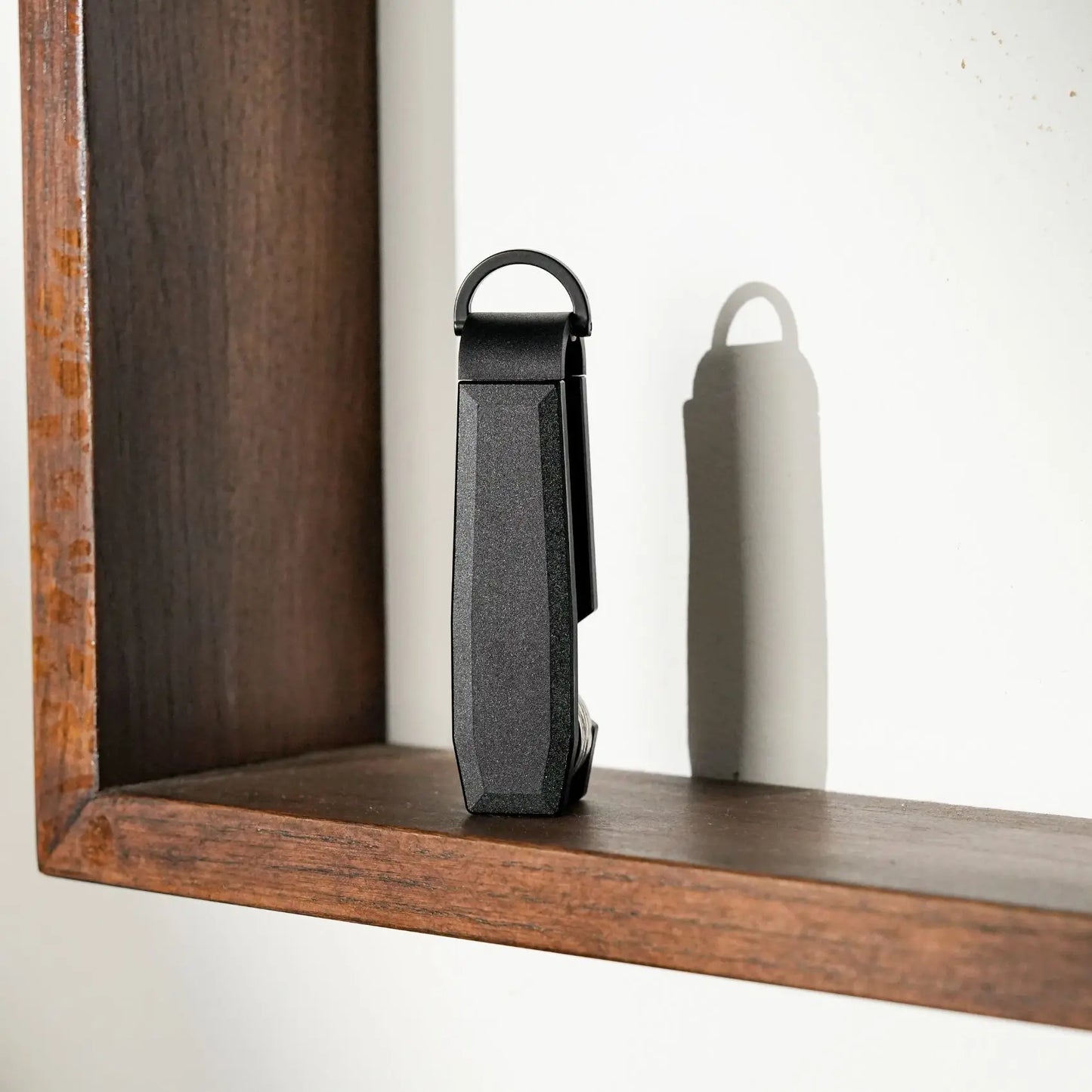Black key holder displayed on a wooden shelf against a white background.