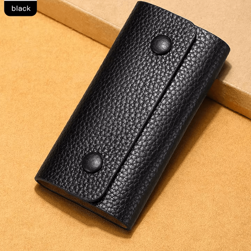 Black leather wallet with two buttons on a beige background