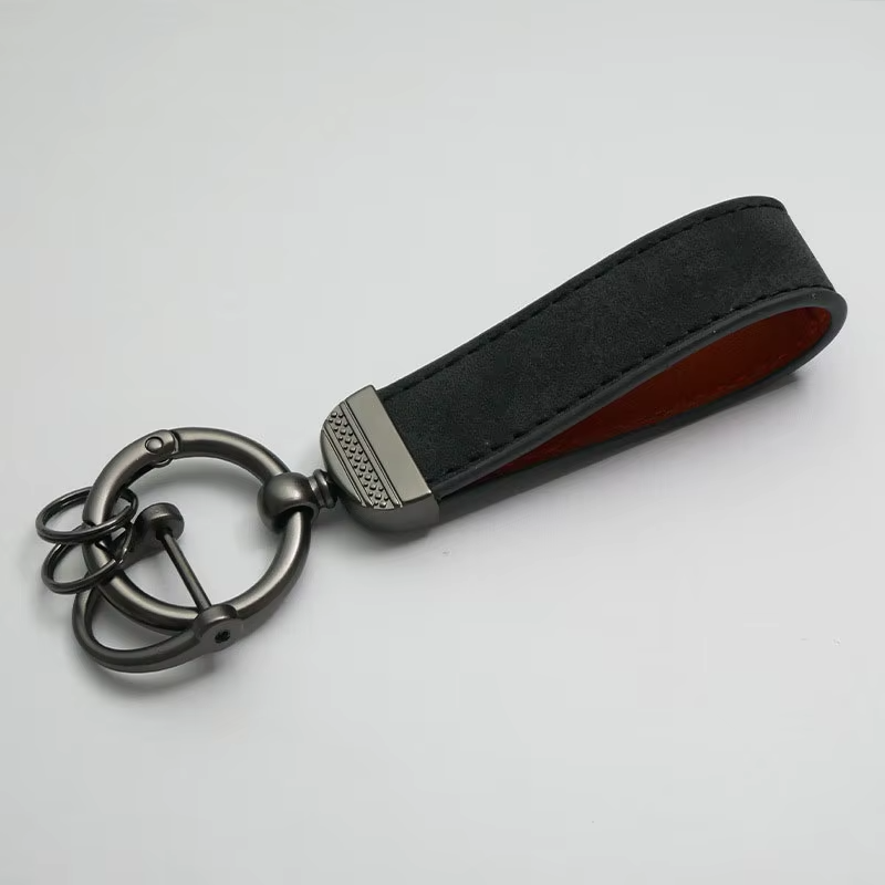 Black leather keychain with metal keyring on a light gray background