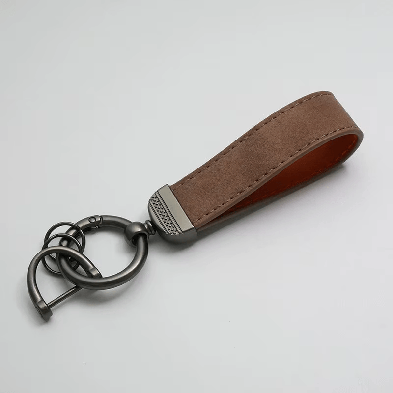Brown leather keychain with metal ring on a light gray background