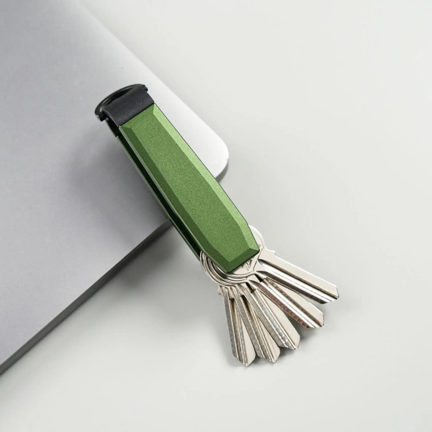 Green Key holder with keys on a light grey background.