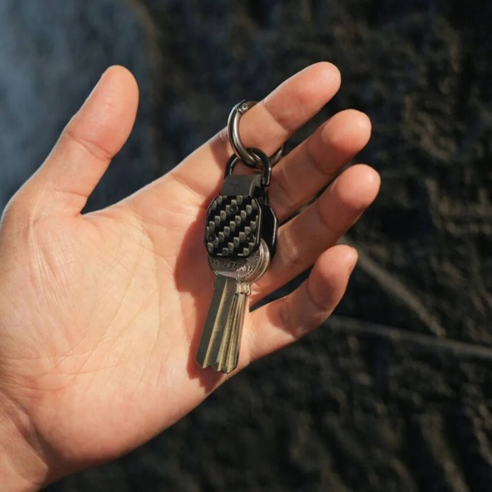Hand holding a key with a keychain against a blurred natural background