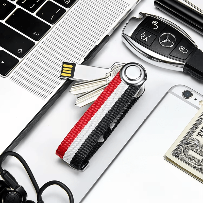 Keychain with USB drive and keys attached, placed on a desk with laptop, money, and car keys.