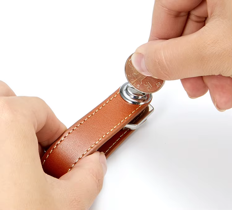 Brown leather key organizer with a coin being used to open.
