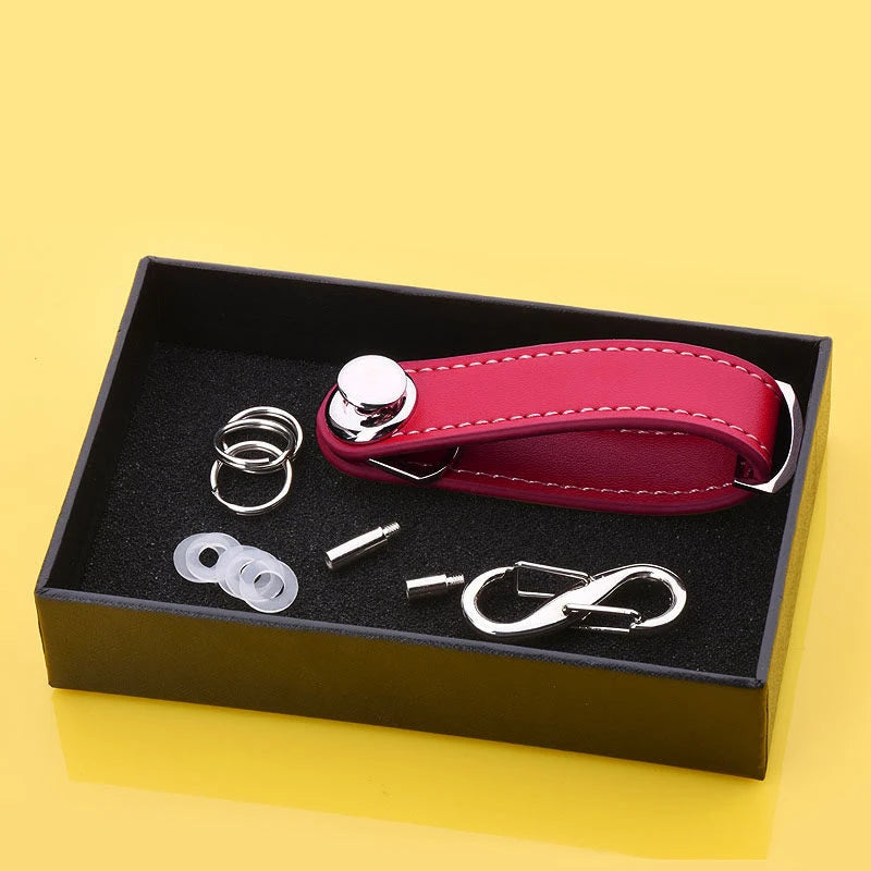 Pink leather keychain with silver keyring and tools in a black box on a yellow background.