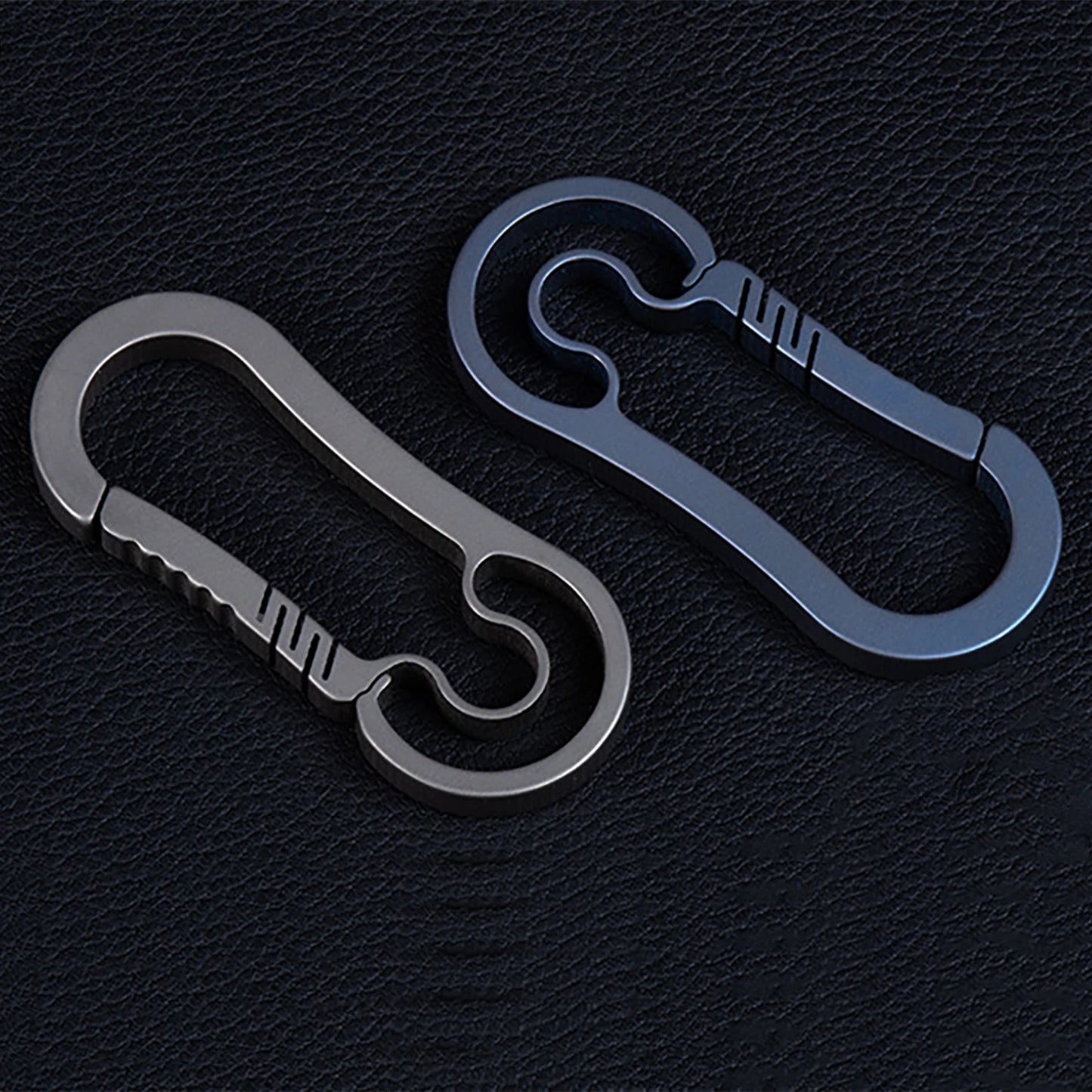 Two metallic carabiners on a black textured background.