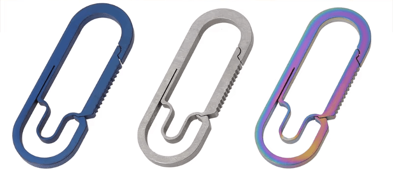 Three titanium carabiners in silver, blue and colorful finish on white background.