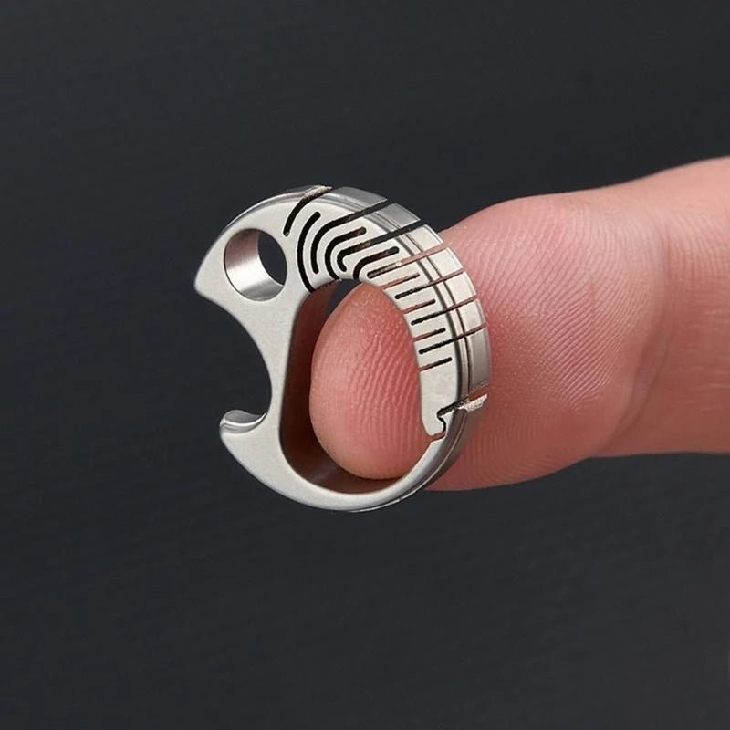 Metallic ring with geometric design on a finger against a dark background.
