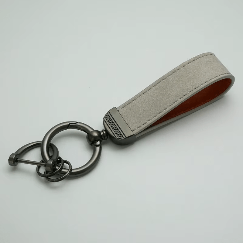 Keychain with beige leather strap on a light gray background
