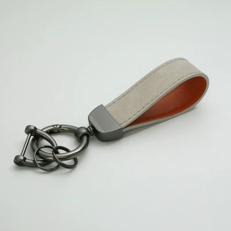 Keychain with beige strap and metal clasp on a light gray background