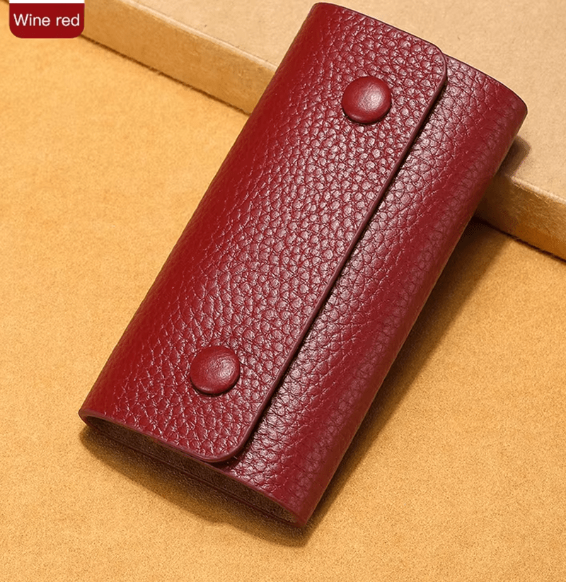 Wine red leather wallet with two buttons on a beige background