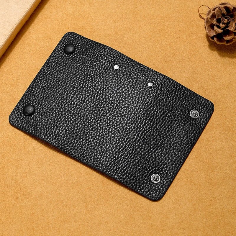 Black leather key holder with metal rivets on a brown background