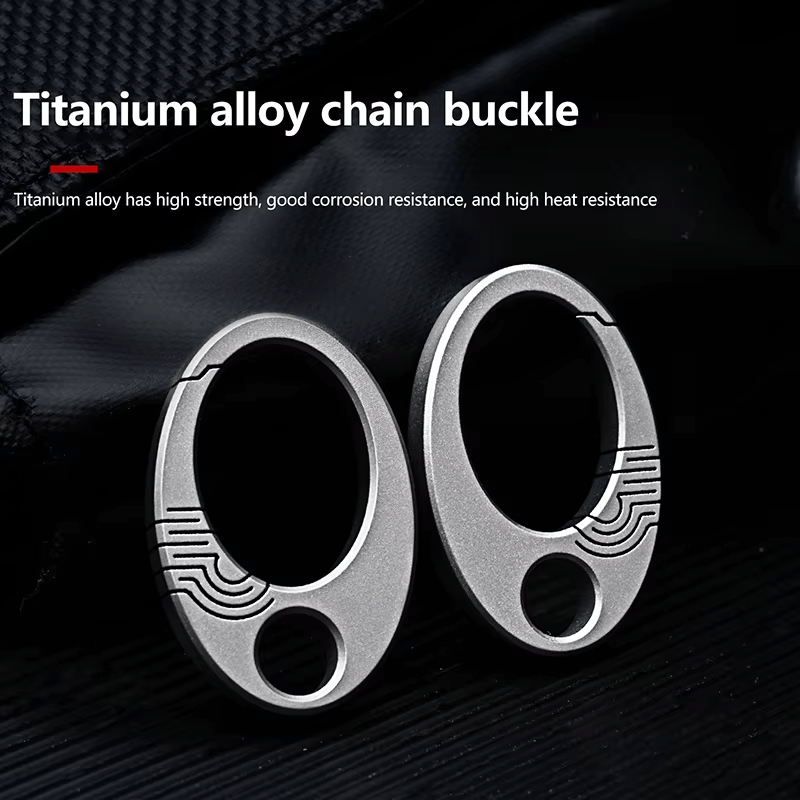 Two titanium alloy oval buckles with engraved details on dark background