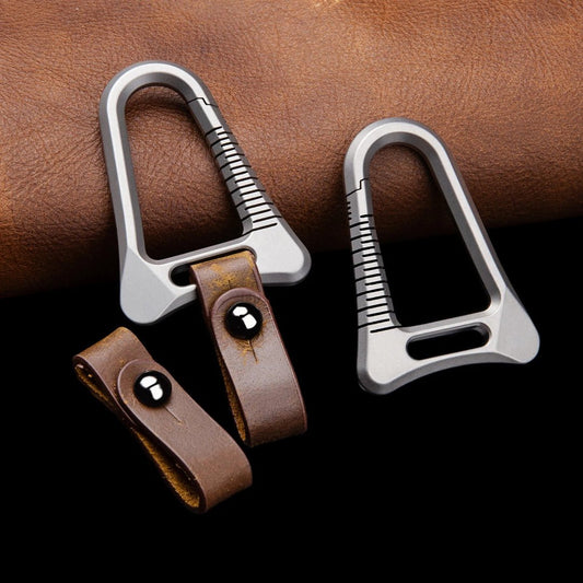 Two silver carabiners with leather straps on a brown leather background