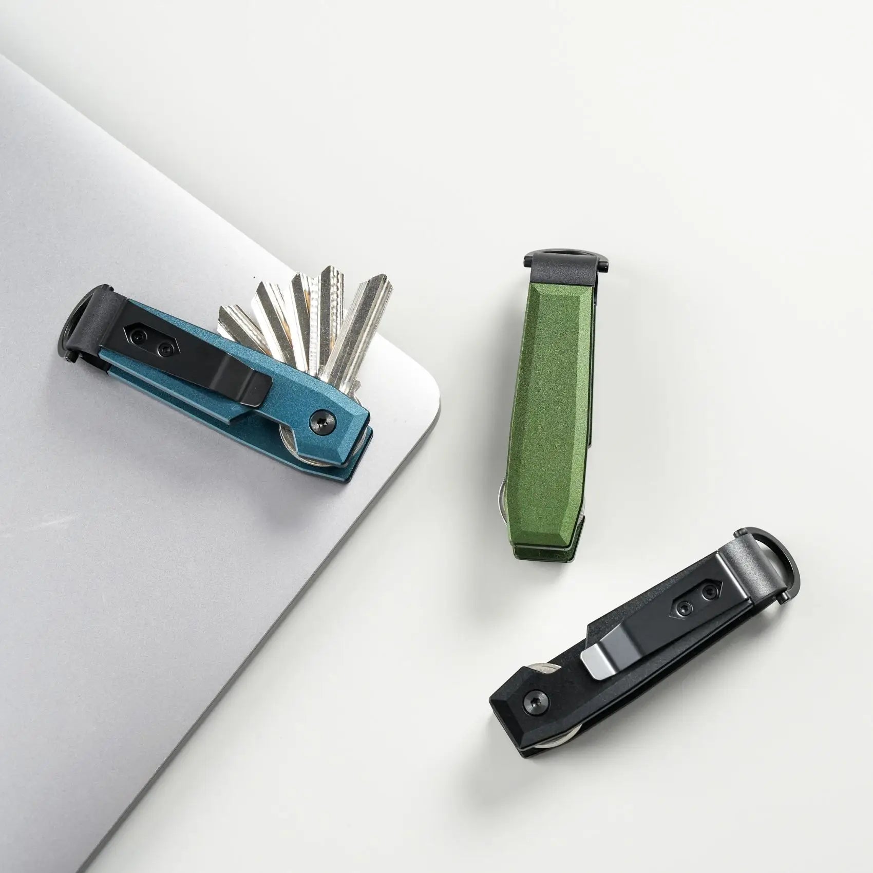 Three multi-tool key organizers on a white surface with keys.