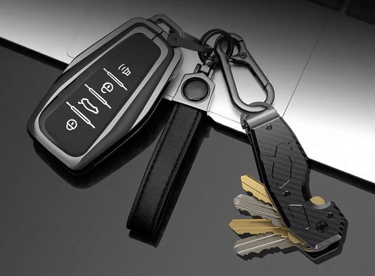 Keychain with car key fob and key organizer and leather strap on a reflective surface.