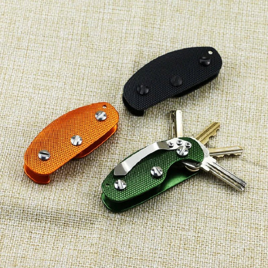 Three key organizers in orange, black, and green on a textured beige surface.