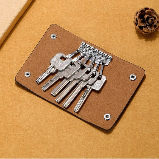 Set of keys on a brown leather key holder against a beige background