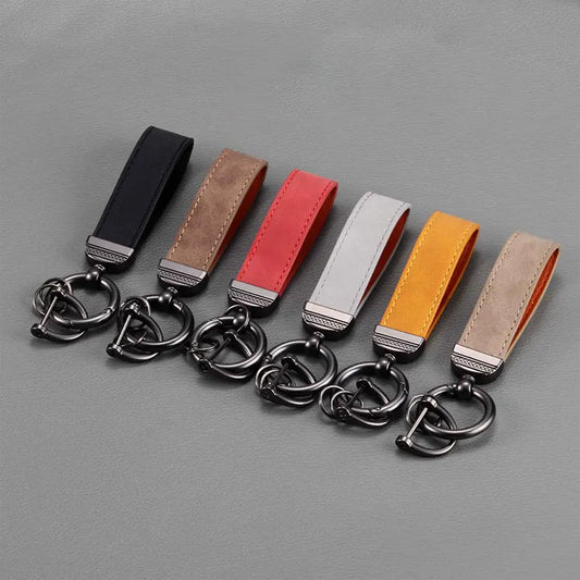 Set of six leather keychains with metal key rings on a gray background