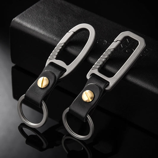 Two titanium carabiners and black keychains with gold screws on a dark background
