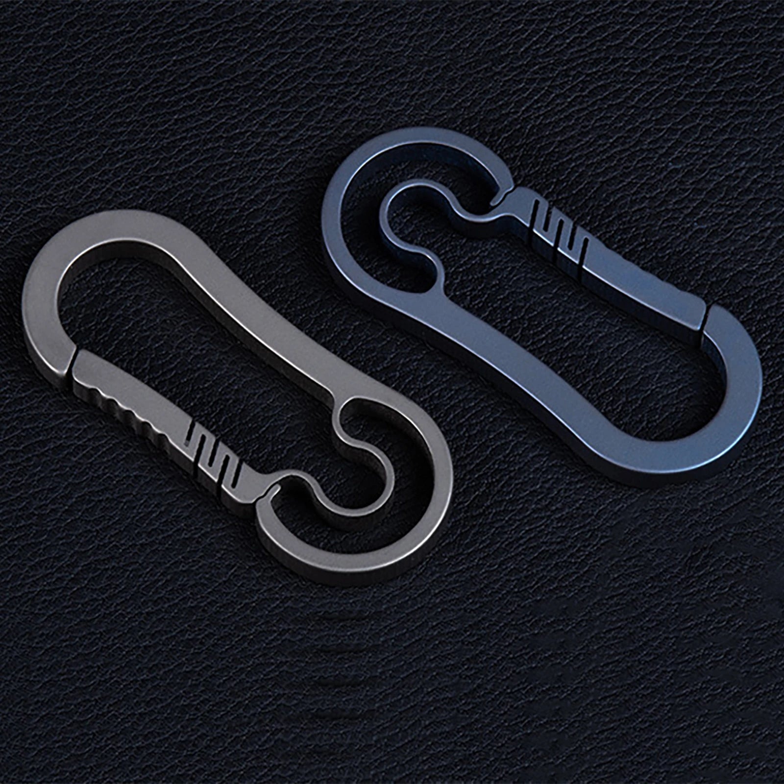Two metallic carabiners on a black textured background.