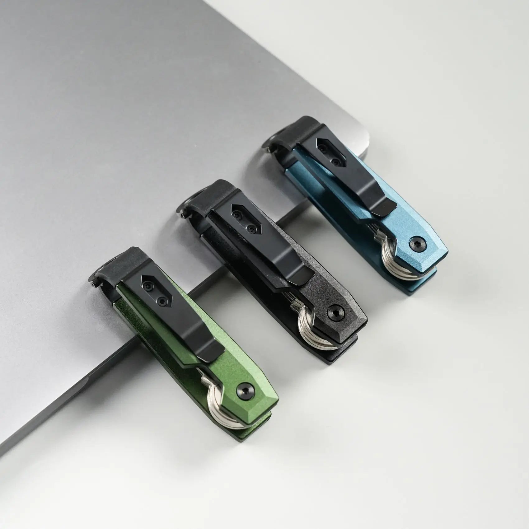 Three multicolored aluminum key organizers on a light gray background