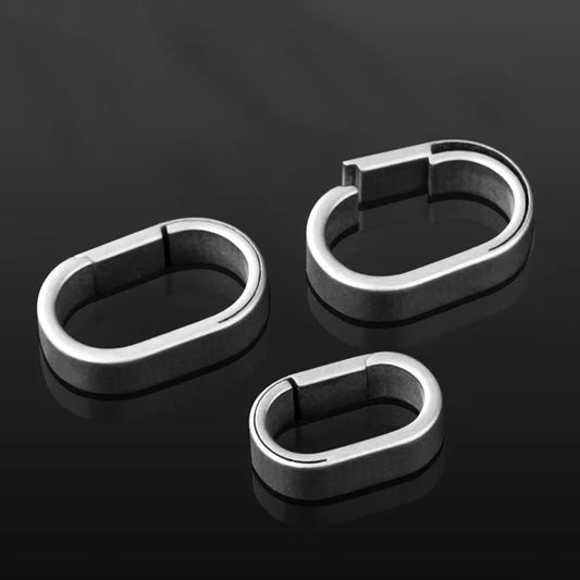 Set of three titanium alloy key rings in different sizes on black surface