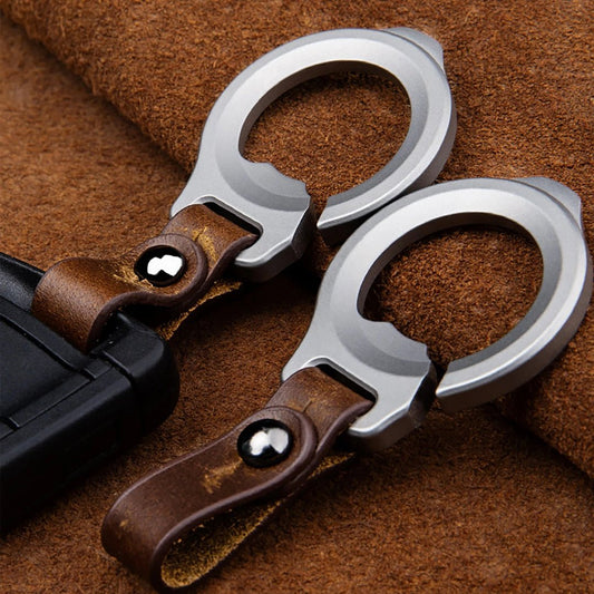 Two silver titanium bottle opener carabiner keychain with brown leather straps on a brown textured background